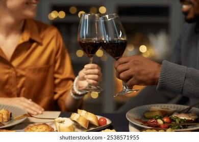 Cropped shot of multiethnic couple enjoying red wine clinking glasses during romantic date at home dinner, copy space - Powered by Shutterstock