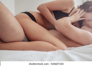 Cropped shot of passionate young couple lying on bed and having sex. Sensual man and woman making love in bedroom.