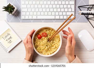 cropped shot of person holding bowl with noodles and chopsticks at workplace - Powered by Shutterstock