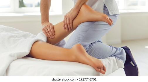 Cropped shot of physiotherapist, chiropractor, professional reflexologist or masseur massaging woman's calf muscle. Patient enjoying leg acupressure therapy lying on massage table in wellness center - Powered by Shutterstock