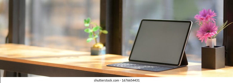 Cropped shot of portable workspace with blank screen tablet on wooden counter bar with copy space and decorations in coffee shop - Powered by Shutterstock