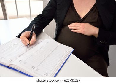 Cropped shot of a pregnant woman planning her maternity leave