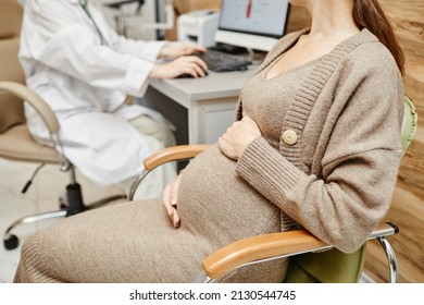Cropped shot of pregnant young woman consulting obgyn in medical clinic with focus on belly, copy space