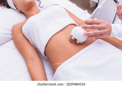 Cropped shot of a professional dermatologist performing radiofrequency lifting procedure on the stomach of a woman. Female client getting rf-lifting treatment on her belly at cosmetology clinic
				