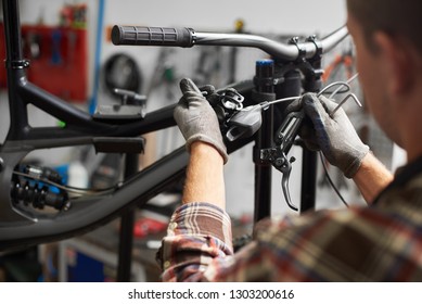 Cropped shot of professional repairman working in bicycle repair shop, mechanic repairing bike using special tool, wearing protective gloves - Powered by Shutterstock