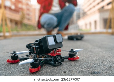 Cropped shot of a proffessional fpv pilot man landing his drone on a street road. Controlling multicopter outdoors experience concept.