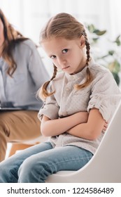 Cropped Shot Of Psychologist Talking To Depressed Child With Crossed Arms While She Looking At Camera