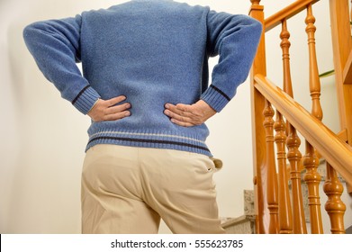 Cropped Shot Of Rear View Of A Senior Man With Lumbago Pain Climbing The Stairs Of His House