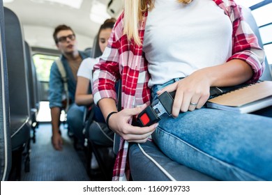 Cropped Shot Of Schoolgirl Fastening Seat Belt At School Bus