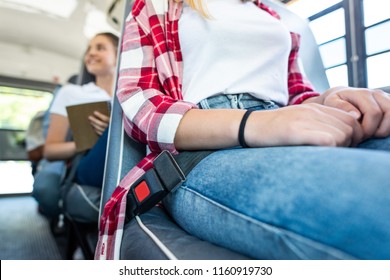 Cropped Shot Of Schoolgirl Sitting At School Bus With Fasten Seat Belt