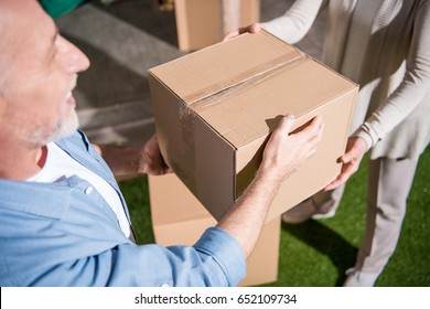 Cropped Shot Of Senior Couple Holding Cardboard Box While Moving Into New House