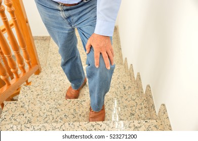 Cropped Shot Of A Senior Man Going Up The Stairs At Home And Touching His Knee By The Pain Of Arthritis