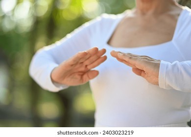 Cropped shot senior woman practicing Chi Kung or Tai Chi in nature. Healthy lifestyle concept. - Powered by Shutterstock