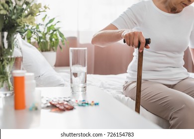 Cropped Shot Of Senior Woman With Walking Stick Sitting On Hospital Bed