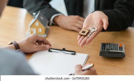 Cropped shot of signing a home purchase contract while the broker holds the house key.