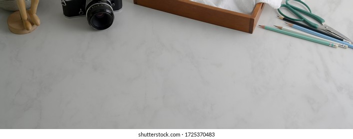 Cropped shot of simple worktable with camera, supplies and copy space on marble desk