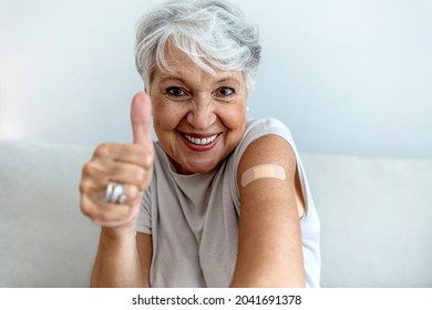 Cropped Shot Of A Smile Senior Woman 70s After Receiving The Coronavirus Covid-19 Vaccine. Old Aged Woman Posing With An Adhesive COVID-19 And Adhesive Bandage On Her Upper Arm. Vaccination Concept.