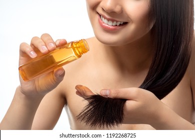 cropped shot of smiling woman pouring oil on split ends isolated on white