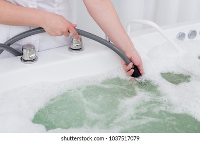 cropped shot of spa salon assistant regulating water in hydro bath