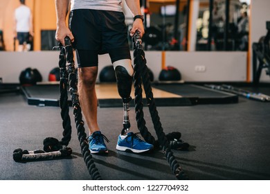 Cropped Shot Of Sportsman With Artificial Leg Working Out With Ropes At Gym