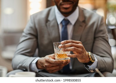 Cropped shot of successful African-American businessman enjoying glass of whiskey in hotel, copy space