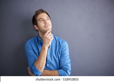Cropped shot of thoughtful young man standing by the wall. - Shutterstock ID 518953855