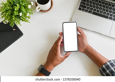 Cropped Shot Top View Of Businessman Hands Using Smartphone Mockup On Office Desk. Blank Screen Mobile Phone For Graphic Display Montage.