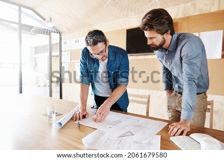 Cropped shot of two architects working on blueprints in their office