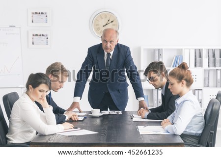 Cropped shot of an unhappy senior boss standing next to the table in the office