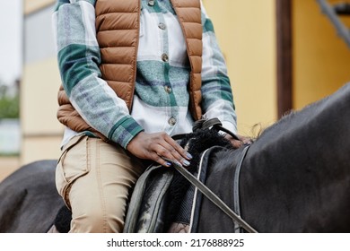 Cropped shot of unrecognizable African American woman riding horse and holding onto reins gently - Powered by Shutterstock