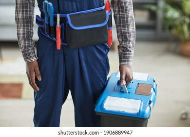 Cropped shot of unrecognizable African-American handyman holding toolbox while standing in home interior, copy space - Powered by Shutterstock