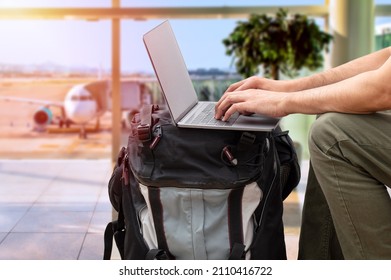 Cropped shot of an unrecognizable digital nomad sitting alone and typing on his laptop during the day at airport