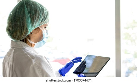 Cropped Shot Of An Unrecognizable Female Nurse Using A Digital Tablet While Standing In A Hospital. Whit A Mask