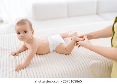 Cropped shot of unrecognizable female therapist doctor doing gymnastics and foot massage to adorable toddler baby. Closeup hand of nurse doing orthopedic leg exercises to newborn child. - Powered by Shutterstock