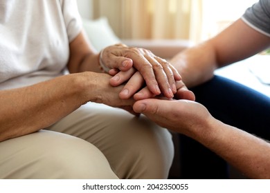 Cropped shot of an unrecognizable male nurse holding his senior patient's hand in comfort. Mother and son hands holding together in love and support after losing loved ones amid coronavirus outbreak. - Shutterstock ID 2042350055