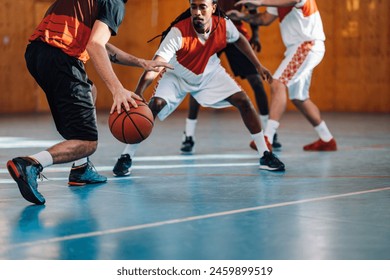 Cropped shot of an unrecognizable professional basketball players playing in a basketball court indoor. Focus on a rear view of a man dribbling the ball during a game. Copy space. - Powered by Shutterstock