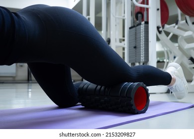 Cropped Shot Of Unrecognizable Slim Sporty Woman Using Foam Roller Massager In Gym To Massages The Muscles Of The Hips And Legs Anterior Thigh Muscle. Stretching And Massaging Muscles