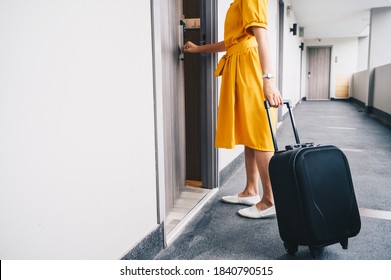 Cropped shot view of tourist woman pulling her luggage to her hotel room after check-in. Conceptual of travel and vacation.
