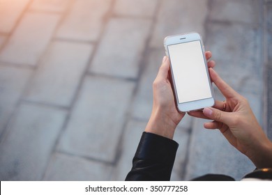 Cropped shot view of woman's hands holding smart phone with blank copy space screen for your text message or information content, female reading text message on cell telephone during in urban setting