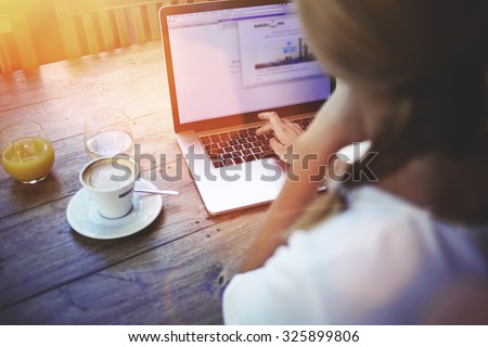 Cropped shot view of a women's hands keyboarding on laptop, young female person working on net-book while sitting in coffee shop indoors, blonde female freelancer connecting to internet via computer 
