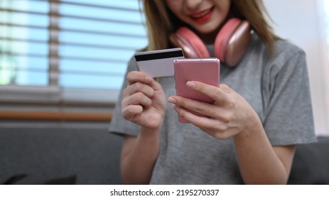 Cropped Shot View Of Young Woman Holding Credit Card And Purchasing Product Via Online Shopping On Mobile Phone