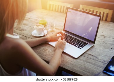 Cropped shot view of young woman keyboarding on laptop computer with blank copy space screen while sitting in cafe, blonde female student working on net-book after her lectures in University,flare sun - Powered by Shutterstock