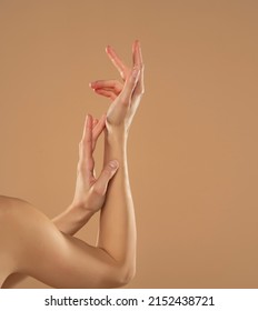 Cropped shot of woman applying cosmetic product on her hands on a beige background. Young woman applying hand cream. - Shutterstock ID 2152438721