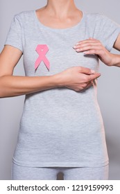 cropped shot of woman with breast cancer awareness pink ribbon on grey background - Shutterstock ID 1219159993