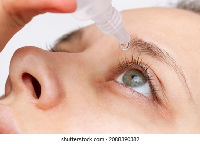 Cropped shot of woman dripping her eye with medicinal drops natural tear.Disease of retina of eye.Conjunctivitis, keratitis, dry eye syndrome, trauma. Treatment of red inflamed and dilated capillaries