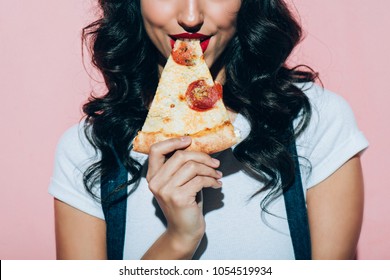 cropped shot of woman eating pizza on pink background 