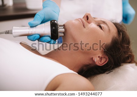 Cropped shot of a woman getting skin tightening treatment on her neck and chin. Beautician doing rf-lifting facial procedure on female client