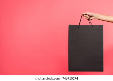 Cropped Shot Of Woman Holding Black Shopping Bag Isolated On Red