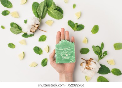 cropped shot of woman holding handcrafted soap on white surface