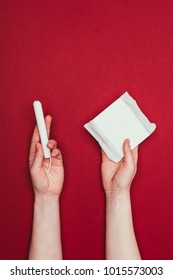 Cropped Shot Of Woman Holding Menstrual Pad And Tampon Isolated On Red